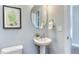 Elegant powder room featuring a pedestal sink, round mirror, and stylish decor for guests at 1019 Tranquil Crk Way, Wake Forest, NC 27587
