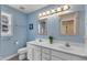 Powder blue bathroom features a dual sink vanity with vanity mirror and updated fixtures, along with natural light at 1123 Poplar Forest Ln, Pittsboro, NC 27312