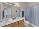 Bright bathroom featuring a double vanity, a large mirror, and a blue striped shower curtain at 12227 Orchardgrass Ln, Raleigh, NC 27614