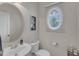 Stylish half bath features a round window and a unique oval mirror at 12227 Orchardgrass Ln, Raleigh, NC 27614