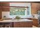 Elegant kitchen with wood cabinetry, stainless steel appliances, and an island, complemented by views of a lush, wooded exterior at 19 Learned Pl, Durham, NC 27705