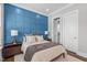 Bedroom displays a blue accent wall, soft neutral bedding, and an ensuite bathroom at 200 Baskerville Ct, Holly Springs, NC 27540