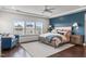 Spacious bedroom with a patterned wall, large windows, ceiling fan, and accent seating at 200 Baskerville Ct, Holly Springs, NC 27540
