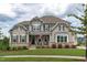 Charming two-story home featuring stone accents, gray siding, and a welcoming front porch with rocking chairs at 200 Baskerville Ct, Holly Springs, NC 27540