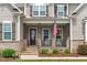 Close-up of inviting front porch with stone accents, rocking chairs, and American flag at 200 Baskerville Ct, Holly Springs, NC 27540