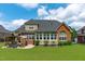 Back exterior view highlights the sunroom, patio, and lush landscaping surrounding this beautiful brick home at 204 Franconia Way, Apex, NC 27502