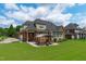 Rear exterior of the brick home features a well-manicured lawn and a charming outdoor living area with a pergola at 204 Franconia Way, Apex, NC 27502