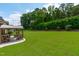 Green backyard and patio with a shaded pergola and a well manicured lawn at 204 Franconia Way, Apex, NC 27502