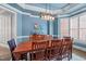 Dining room with blue walls, tray ceiling, wood table, and buffet, illuminated by an industrial light fixture at 204 Franconia Way, Apex, NC 27502