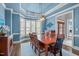 Blue dining room with a wood table, tray ceiling, and view through the doorway into the office and foyer at 204 Franconia Way, Apex, NC 27502