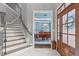 Light-filled foyer with staircase, marble floors, and a view into the dining room with blue walls and trim at 204 Franconia Way, Apex, NC 27502
