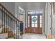 Bright foyer with wood door with glass inserts, white marble floors, and staircase with decorative iron railings at 204 Franconia Way, Apex, NC 27502