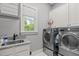 Bright laundry room featuring gray walls, granite countertop, and high-end washer and dryer at 204 Franconia Way, Apex, NC 27502