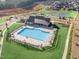 Aerial view of a sparkling pool with lounge chairs, clubhouse, tennis court, playground, and surrounding homes at 212 Sea Trail St, Hillsborough, NC 27278