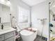 Bright bathroom with a free-standing tub, decorative window, and a marble tiled shower at 214 Ashdown Forest Ln, Cary, NC 27519