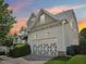A two car garage with decorative doors in a home with neutral toned siding at sunset at 214 Ashdown Forest Ln, Cary, NC 27519
