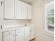 Bright laundry room with ample white cabinetry, sink, countertop space, and window at 214 Ashdown Forest Ln, Cary, NC 27519