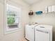 Functional laundry room with washer, dryer, window, and shelving for convenient storage at 214 Ashdown Forest Ln, Cary, NC 27519