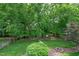 Lush backyard featuring mature trees, green lawn, and a charming fire pit area at 221 Roebling Ln, Cary, NC 27513
