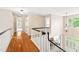 Bright hallway with hardwood floors leading to other rooms, a staircase, and a view of the foyer at 221 Roebling Ln, Cary, NC 27513