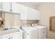 Efficient laundry room includes white cabinets, utility sink, washer, and dryer at 221 Roebling Ln, Cary, NC 27513