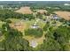 Expansive aerial view of a well-manicured community with a picturesque farmhouse-style home nestled among lush trees at 2229 Neills Creek Rd, Lillington, NC 27546