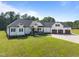Desirable white farmhouse-style home with a sprawling lawn, complemented by a long driveway and mature trees at 2229 Neills Creek Rd, Lillington, NC 27546