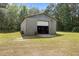 A gray cinder block outbuilding with a roll up door in a grassy setting at 2229 Neills Creek Rd, Lillington, NC 27546