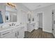 Bright bathroom with gray cabinets, dual sinks, framed mirrors, and wood look floors at 2300 Ginger Gold Court, Apex, NC 27539