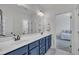 Bathroom with double vanity, blue cabinets, and view into bedroom at 2300 Ginger Gold Court, Apex, NC 27539