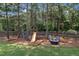 Backyard play area with swing set, slide, mature trees, and an Adirondack chair seating area at 2300 Ginger Gold Court, Apex, NC 27539