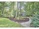 A gravel path curves through the lawn, leading to a charming two-story home surrounded by lush trees at 2334 Dawn Trl, Durham, NC 27712