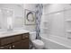 Well-lit bathroom with a wood vanity, white countertop, and a tub-shower combo with a patterned curtain at 2769 Cassius Dr, Apex, NC 27502