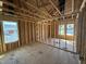 Spacious unfinished room with exposed framing, wood subfloor, and two windows offering natural light and neighborhood views at 29 Chloe Ct, Selma, NC 27576