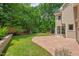 Spacious backyard with a stone patio and lush lawn, framed by a charming stone wall and privacy fence at 3 White Ash Dr, Durham, NC 27712