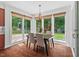 Dining room with wood floors and large windows overlooking a private outdoor stone patio and lush backyard at 3 White Ash Dr, Durham, NC 27712