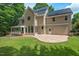 Expansive backyard with a stone patio and screened porch, complemented by lush greenery and solar panels at 3 White Ash Dr, Durham, NC 27712