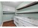 Bright laundry room with wood-look floors, white cabinets, marble countertop, and wood shelving at 3 White Ash Dr, Durham, NC 27712
