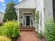 Welcoming home entrance with a brick walkway, blossoming greenery, and glass-paneled door at 31 W Madison, Pittsboro, NC 27312