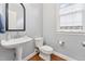 Stylish half bathroom featuring a pedestal sink, sleek mirror, and modern fixtures at 325 Wescott Ridge Dr, Holly Springs, NC 27540
