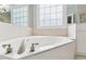 Close up of a luxurious soaking tub with stylish fixtures and tile work, and a frosted window at 325 Wescott Ridge Dr, Holly Springs, NC 27540