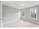 Bright bedroom features neutral carpet and paint, two large windows, and white trim throughout at 325 Wescott Ridge Dr, Holly Springs, NC 27540