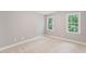 Neutral bedroom featuring two large windows that flood the space with natural light, carpeted floors, and light gray walls at 325 Wescott Ridge Dr, Holly Springs, NC 27540