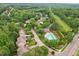 Aerial view showcasing a community pool with manicured landscaping, surrounded by trees, homes, and a parking lot at 325 Wescott Ridge Dr, Holly Springs, NC 27540