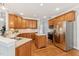 Well-lit kitchen featuring wooden cabinetry, stainless steel appliances, an island, and hardwood floors at 325 Wescott Ridge Dr, Holly Springs, NC 27540