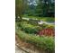 Landscaped entrance with a stone 'Woodscreek' sign, accented by red flowers and lush greenery at 3300 Barnsley Ln, Raleigh, NC 27604