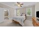 The bedroom features dual windows, a ceiling fan, and a view to the ensuite bathroom and shower at 404 Wanderview Ln, Holly Springs, NC 27540