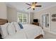 The bedroom features windows, a ceiling fan, and a view to the ensuite bathroom at 404 Wanderview Ln, Holly Springs, NC 27540