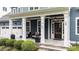 Welcoming front porch featuring stone steps, white columns, comfortable seating, hanging lanterns, and a decorative glass front door at 404 Wanderview Ln, Holly Springs, NC 27540