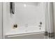 Clean, bright white tiled bathroom with bathtub, curtain, and shelves at 407 Gooseneck Dr # B1, Cary, NC 27513